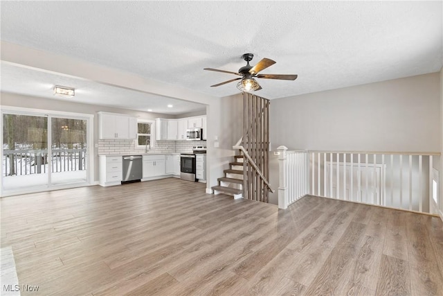 unfurnished living room with sink, a textured ceiling, and light wood-type flooring