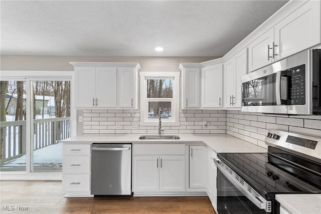 kitchen featuring appliances with stainless steel finishes, sink, a wealth of natural light, and white cabinets