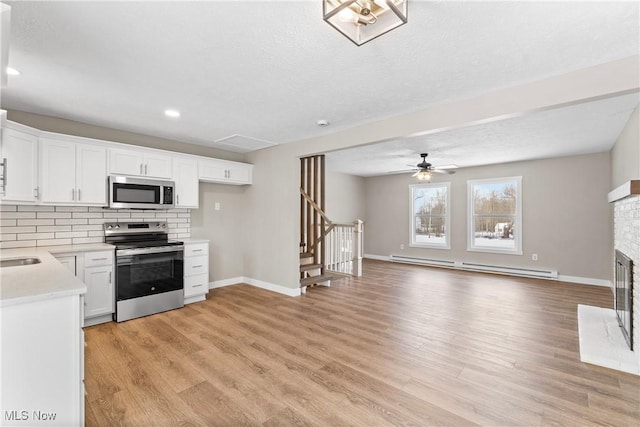 kitchen featuring stainless steel appliances, tasteful backsplash, light hardwood / wood-style floors, white cabinets, and a baseboard radiator