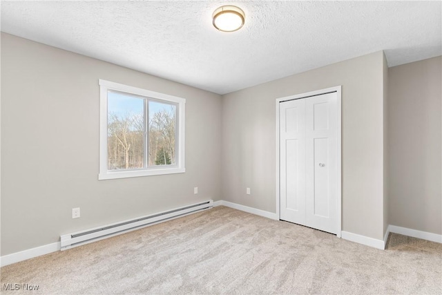 unfurnished bedroom featuring light carpet, a baseboard radiator, and a textured ceiling