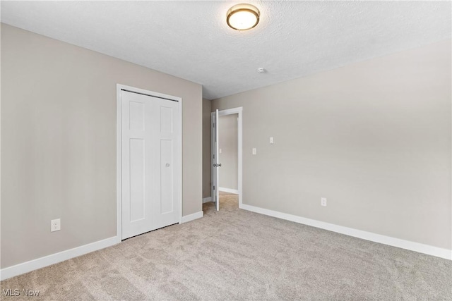 unfurnished bedroom with light colored carpet, a closet, and a textured ceiling