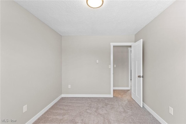 unfurnished room featuring light colored carpet and a textured ceiling