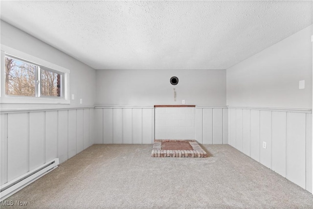 spare room with carpet floors, a textured ceiling, and baseboard heating