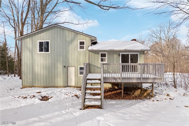 snow covered rear of property with a wooden deck