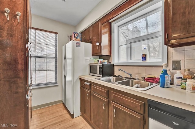 kitchen with dark brown cabinetry, sink, backsplash, and light hardwood / wood-style floors