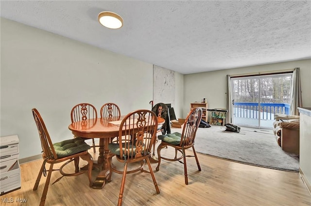 dining room featuring a textured ceiling and light hardwood / wood-style floors