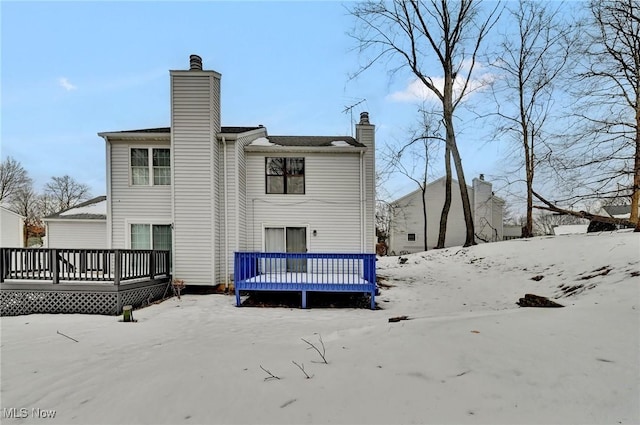 snow covered back of property with a deck