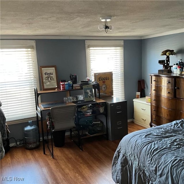 bedroom with hardwood / wood-style flooring, a textured ceiling, and multiple windows