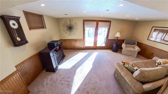 sitting room featuring crown molding, wooden walls, and light carpet