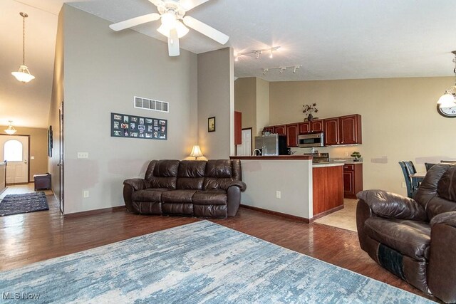 living room featuring dark wood-type flooring, ceiling fan, track lighting, and high vaulted ceiling