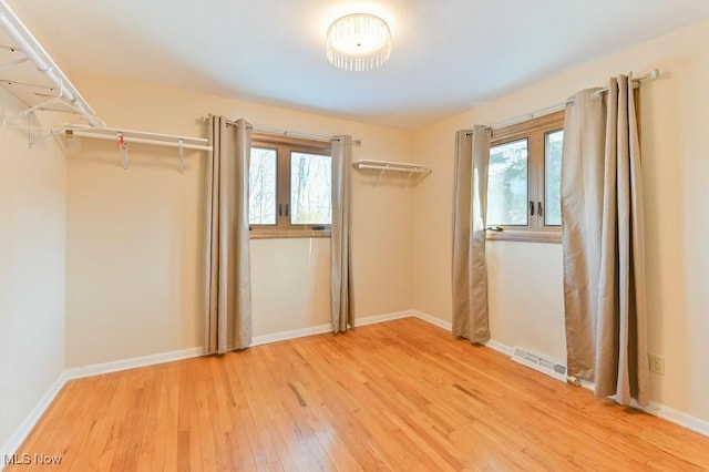 unfurnished bedroom with hardwood / wood-style floors and multiple windows