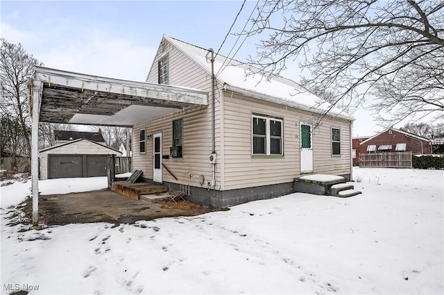 view of snowy exterior featuring a garage and an outdoor structure