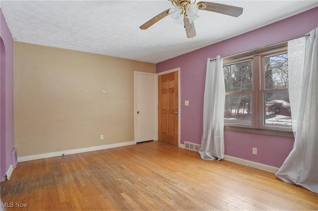 empty room with a textured ceiling, light hardwood / wood-style flooring, and ceiling fan