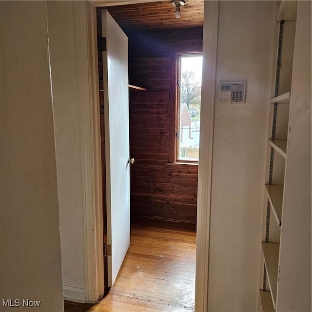 hall with wood ceiling, light hardwood / wood-style floors, and wood walls