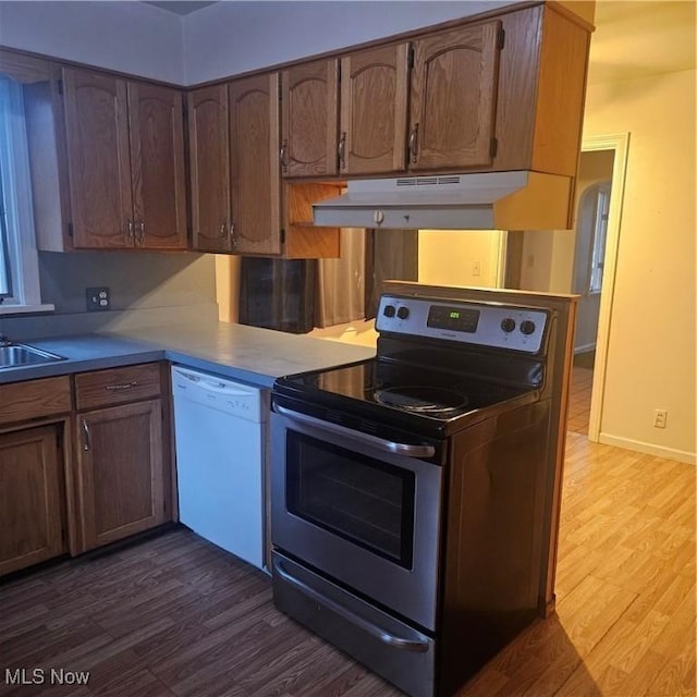 kitchen featuring dark wood-type flooring, dishwasher, sink, and stainless steel electric range