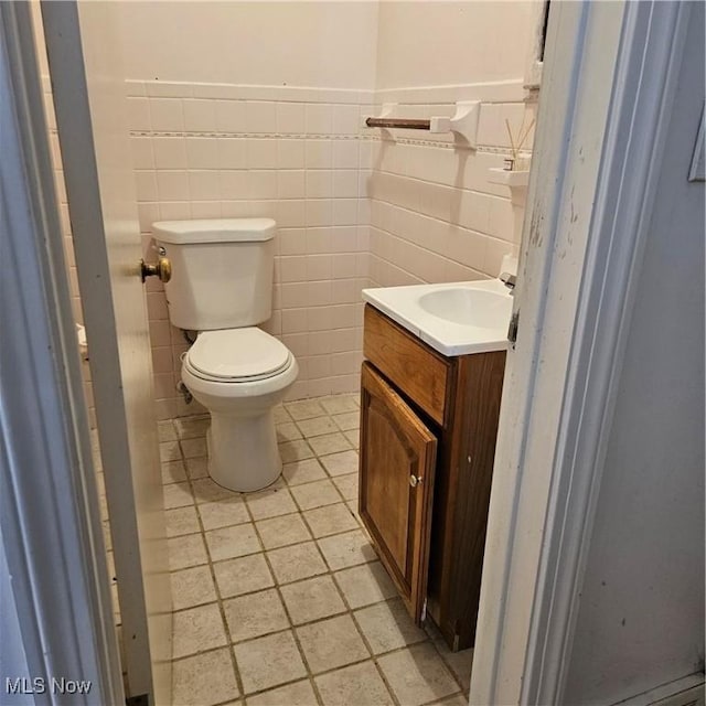 bathroom featuring vanity, tile walls, and toilet