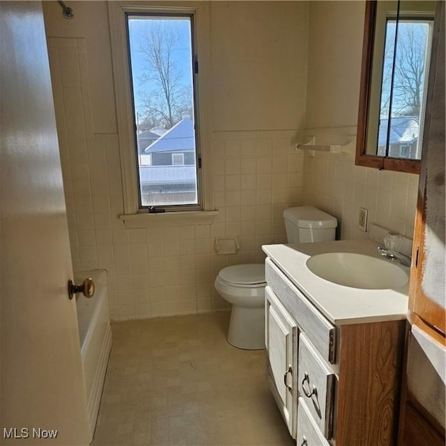 bathroom with vanity, plenty of natural light, tile walls, and toilet