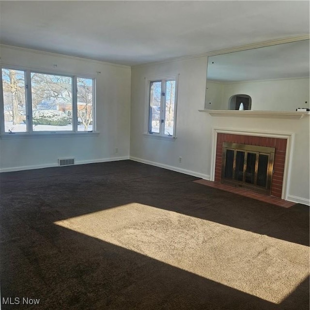 unfurnished living room featuring ornamental molding, a fireplace, and dark carpet