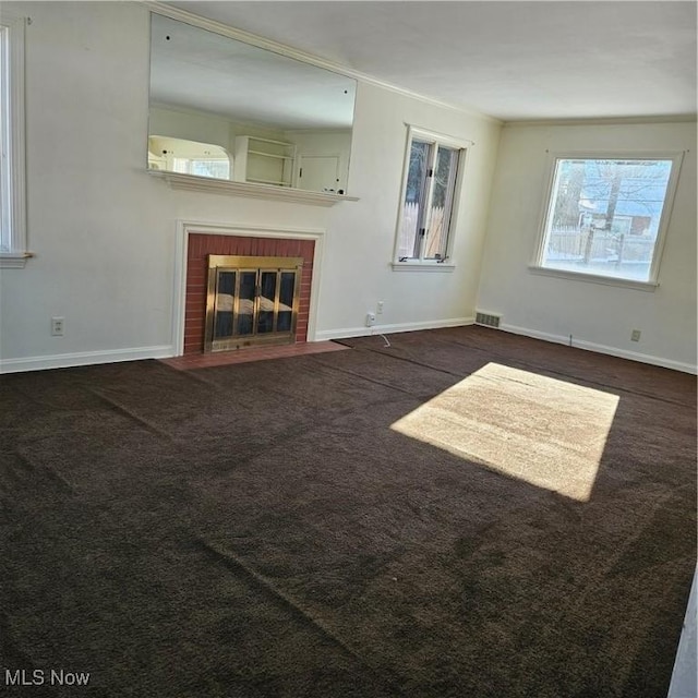 unfurnished living room with dark colored carpet and a brick fireplace