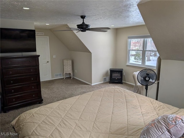 carpeted bedroom featuring lofted ceiling, ceiling fan, a textured ceiling, and a wood stove