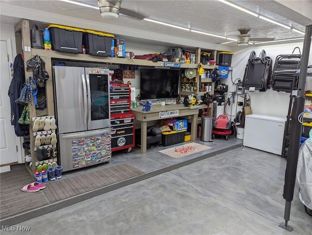 garage featuring a workshop area, fridge, and stainless steel refrigerator