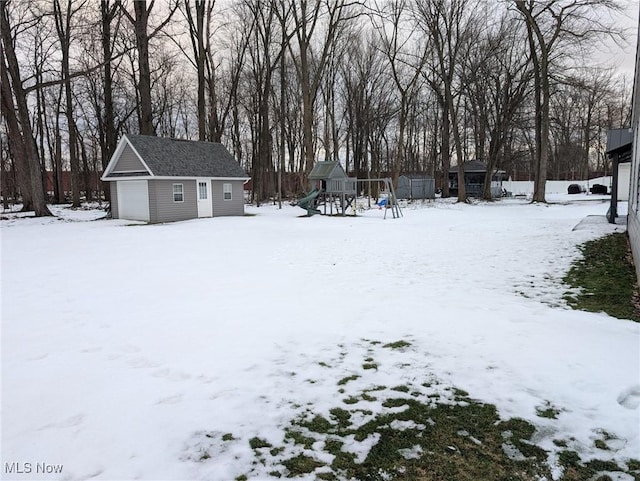 snowy yard featuring a storage shed and a playground