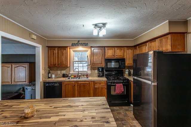 kitchen with butcher block countertops, sink, tasteful backsplash, ornamental molding, and black appliances