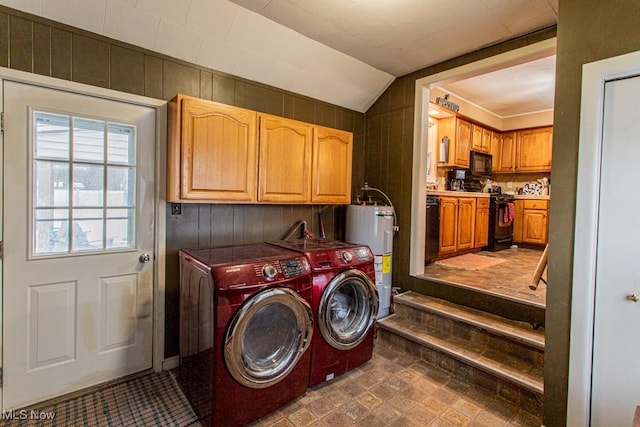 clothes washing area with water heater, cabinets, wooden walls, and washer and dryer