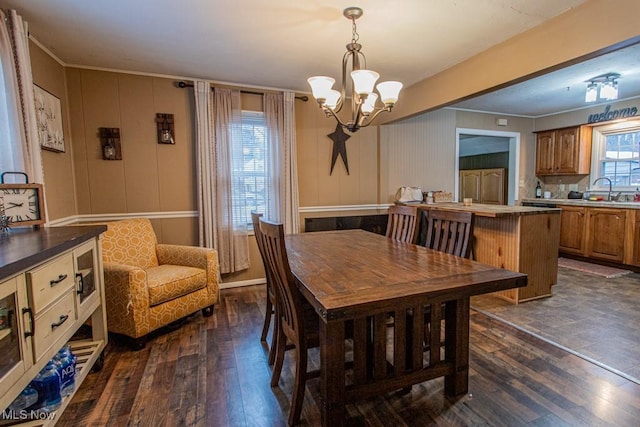 dining space featuring ornamental molding, dark hardwood / wood-style floors, sink, and an inviting chandelier