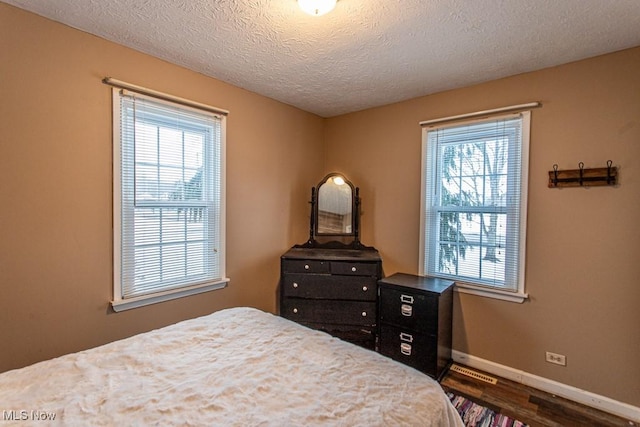 bedroom with a textured ceiling and dark hardwood / wood-style flooring