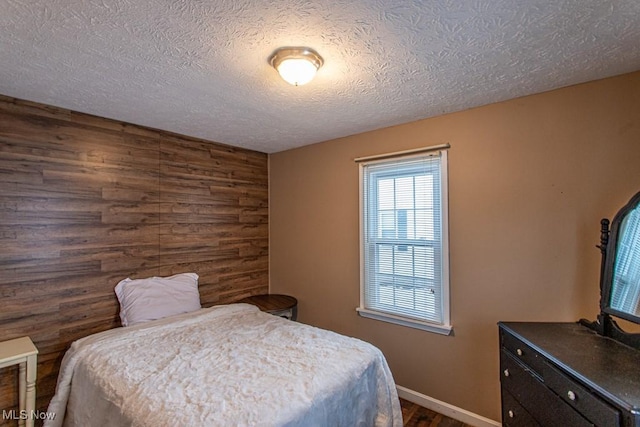 bedroom with wooden walls and a textured ceiling