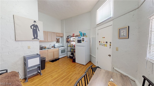 kitchen with sink, white appliances, light hardwood / wood-style floors, and light brown cabinets