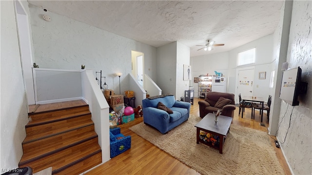 living room featuring ceiling fan, wood-type flooring, and a textured ceiling