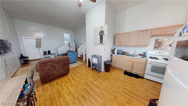 kitchen featuring sink, light brown cabinetry, white gas stove, and light hardwood / wood-style flooring