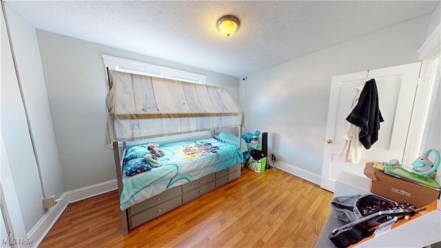 bedroom featuring light hardwood / wood-style flooring and a textured ceiling