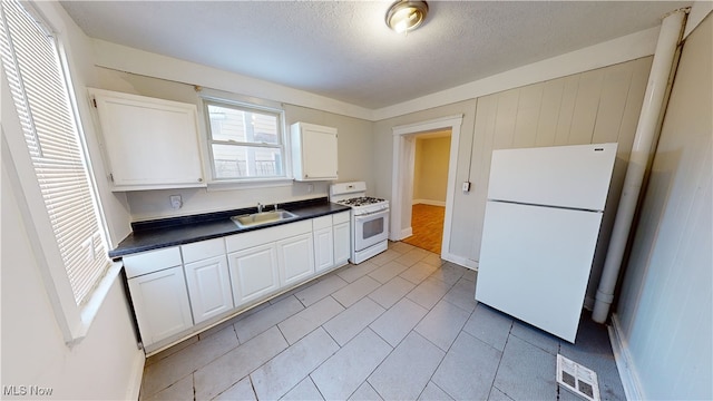 kitchen featuring white appliances, sink, a textured ceiling, and white cabinets