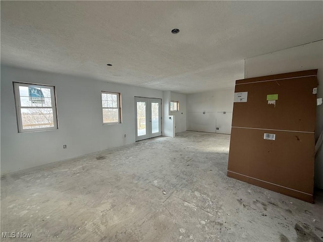 empty room featuring french doors and a textured ceiling