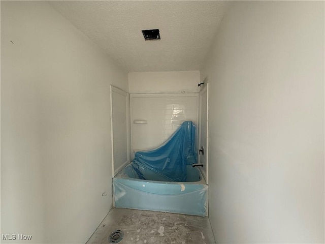 bathroom featuring tub / shower combination, concrete floors, and a textured ceiling