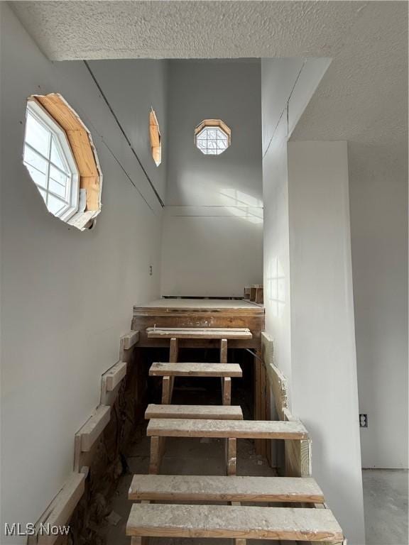 stairway featuring concrete flooring and a textured ceiling