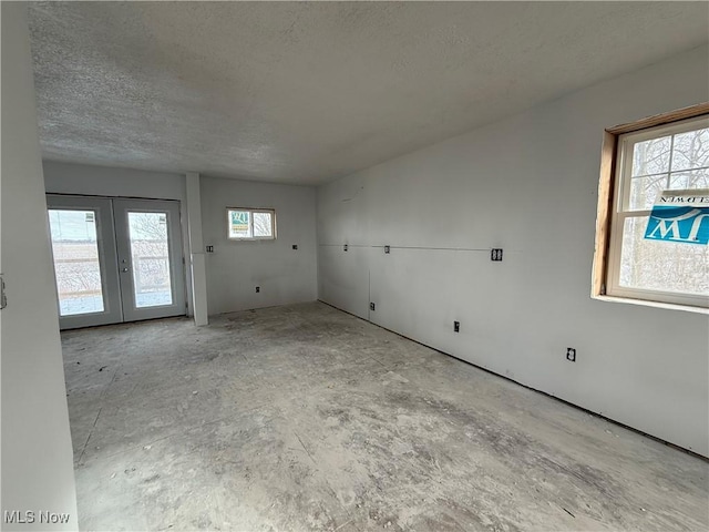 unfurnished room featuring a wealth of natural light, a textured ceiling, and french doors