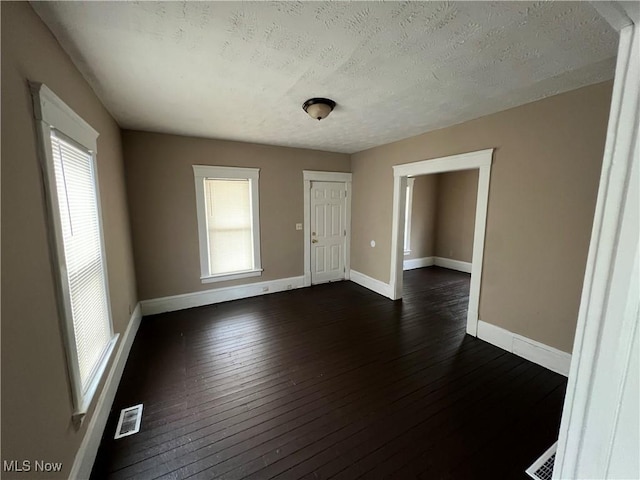 unfurnished room with dark hardwood / wood-style floors and a textured ceiling