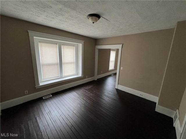 unfurnished room with dark hardwood / wood-style flooring and a textured ceiling