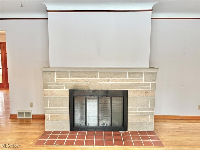 room details featuring crown molding, a stone fireplace, and hardwood / wood-style floors