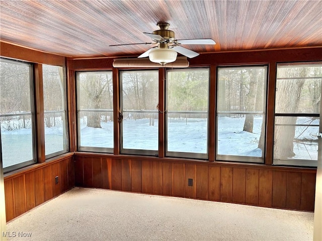 unfurnished sunroom with ceiling fan, wood ceiling, and a healthy amount of sunlight