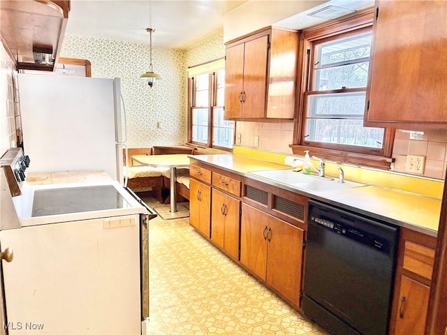 kitchen with white appliances, decorative light fixtures, and sink