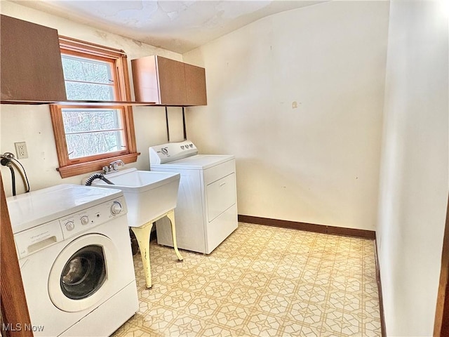 clothes washing area with cabinets, sink, and washer and clothes dryer