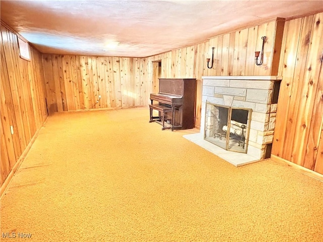 basement with a stone fireplace, carpet floors, and wood walls