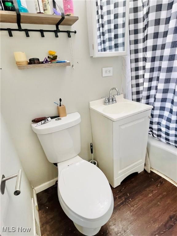 full bathroom with shower / tub combo with curtain, vanity, hardwood / wood-style flooring, and toilet