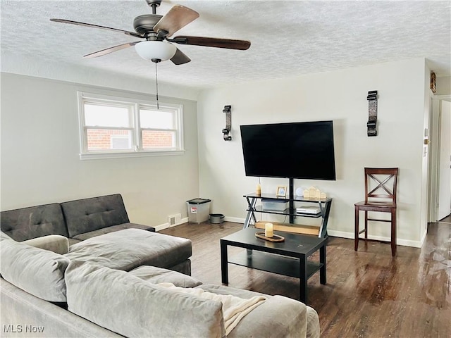 living room featuring ceiling fan, dark hardwood / wood-style flooring, and a textured ceiling