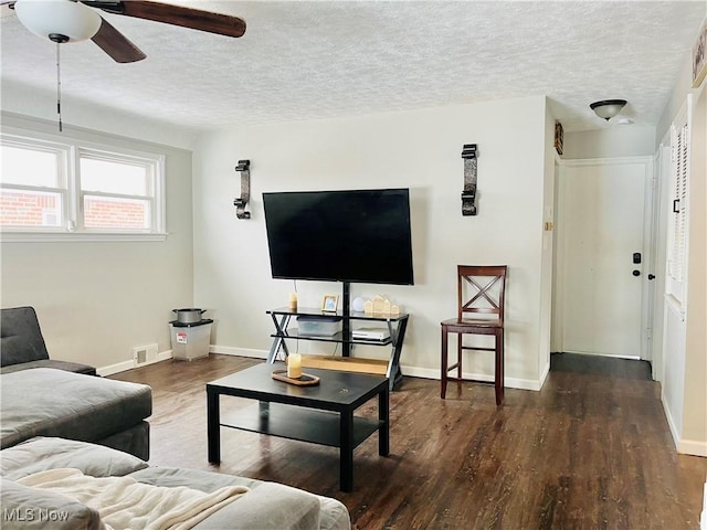 living room with dark hardwood / wood-style flooring, ceiling fan, and a textured ceiling